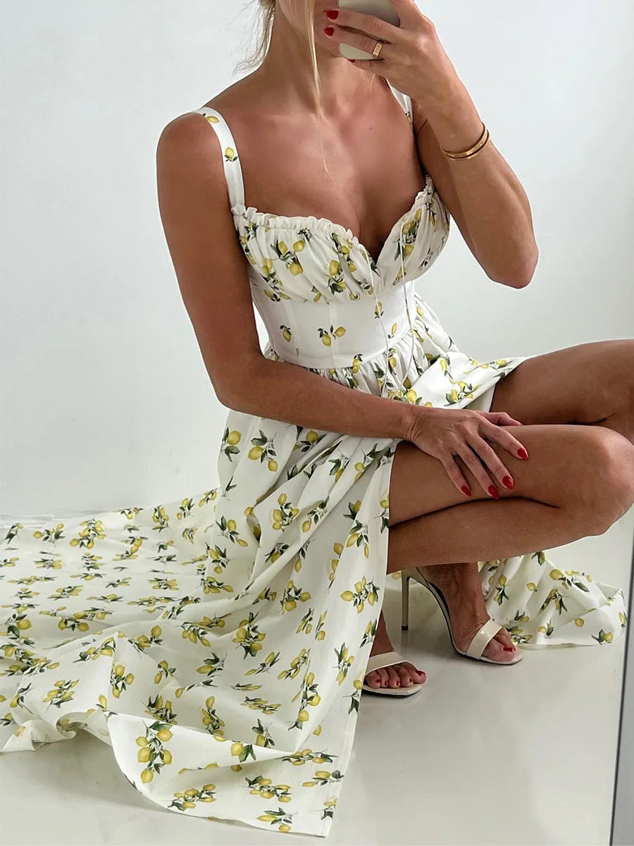 Woman wearing a white floral dress sitting on a white surface.