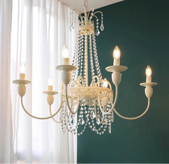 Chandelier with crystal accents against a green wall and white curtains