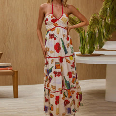Woman wearing a colorful dress with a kitchen-themed pattern in a room with wooden walls and a table.