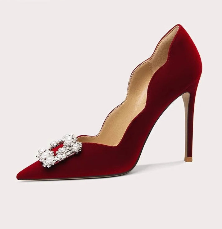 Red high-heeled shoe with a decorative bow on a light gray background