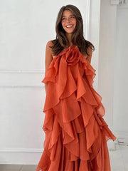 Woman wearing an orange ruffled dress against a white wall