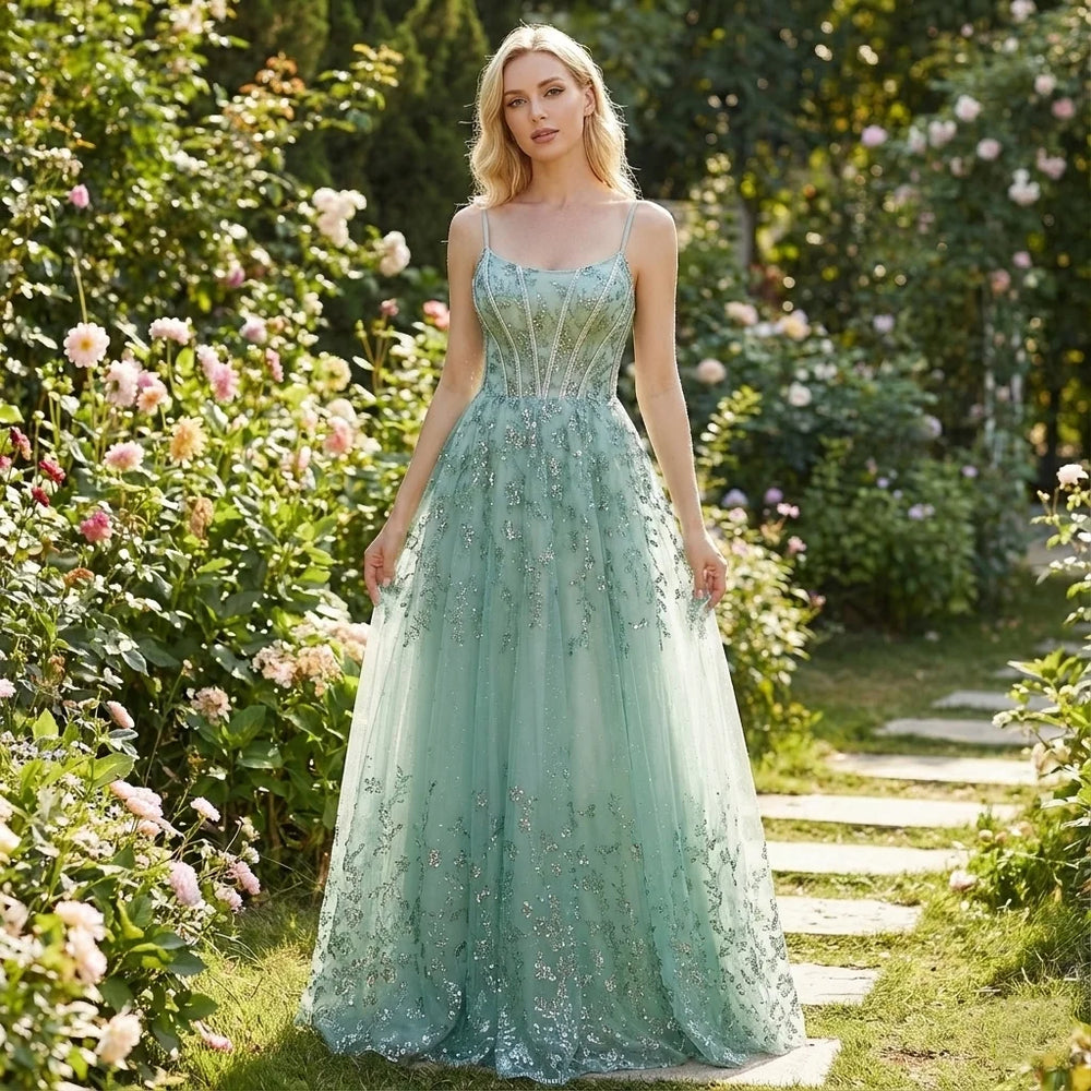 Woman in a light green lace dress standing in a garden with flowers and a path.