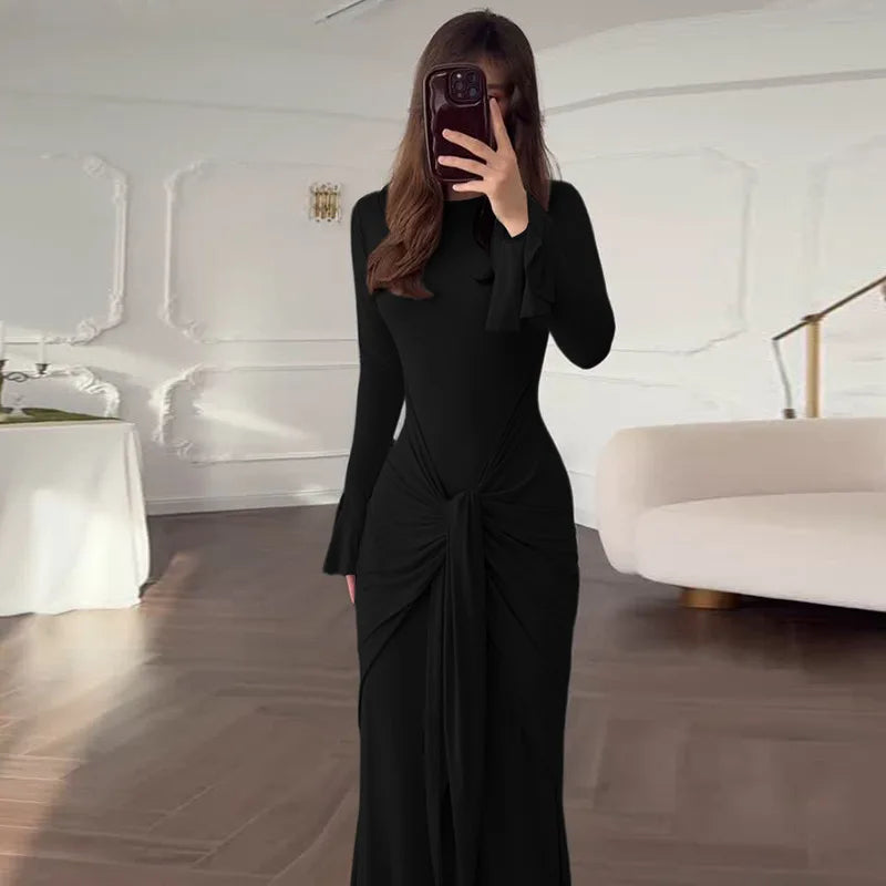 Person wearing a black dress in a modern room with white walls and furniture.