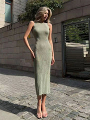 Golden Atelier green sweater dress with a bodycon silhouette and a distressed detail. The sleeveless dress is modeled on a woman in a fall setting. Green