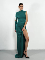 Woman wearing a green evening gown with a high slit on a white background
