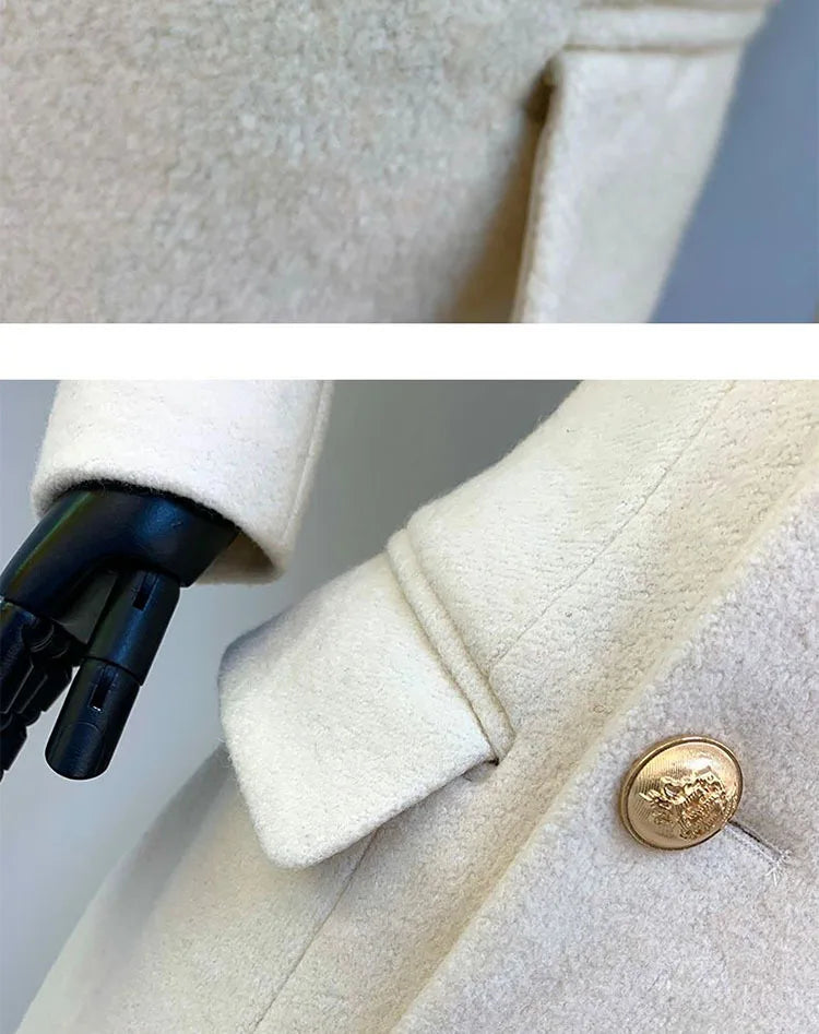 Close-up of a beige coat with a gold button, held by a black stand against a neutral background.