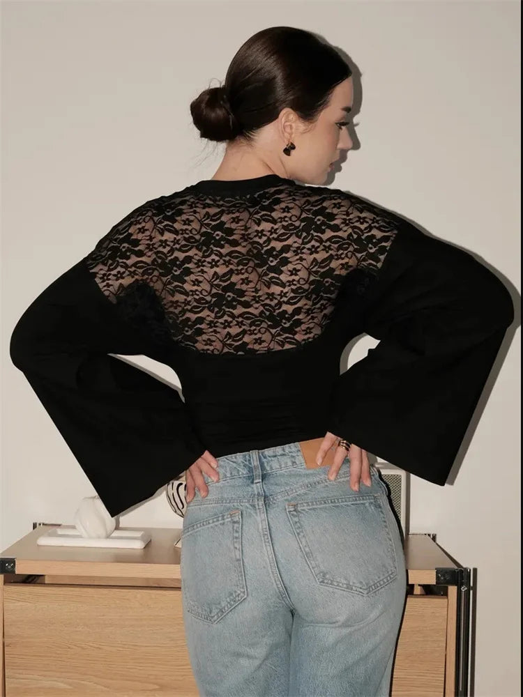 Person wearing a black lace top and light blue jeans in an indoor setting