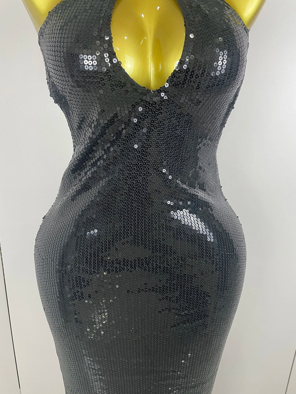 Black sequin dress on a mannequin against a white background