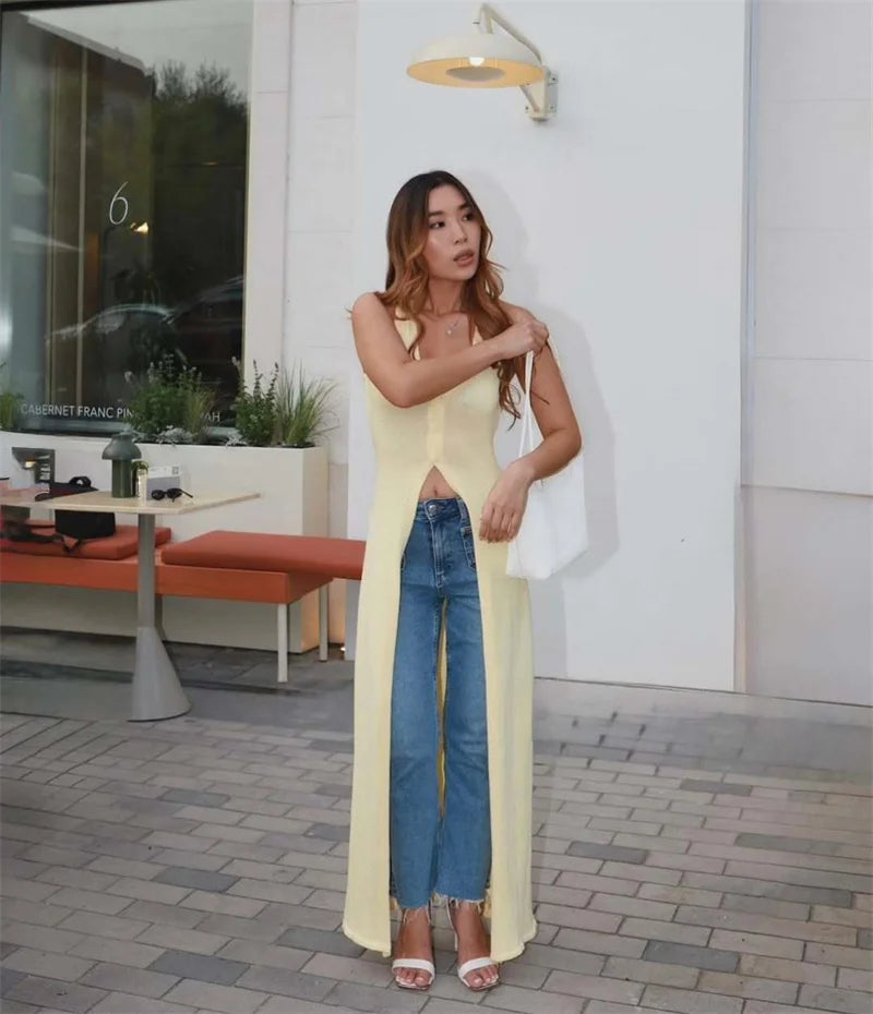 Woman wearing a long yellow dress with blue jeans underneath, standing in an outdoor setting.