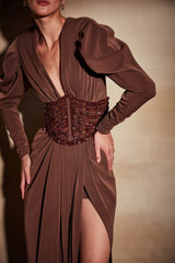 Brown evening gown with a deep neckline and slit skirt on a model against a neutral background