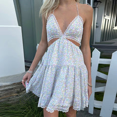 Woman wearing a white floral dress with cut-out design outdoors.