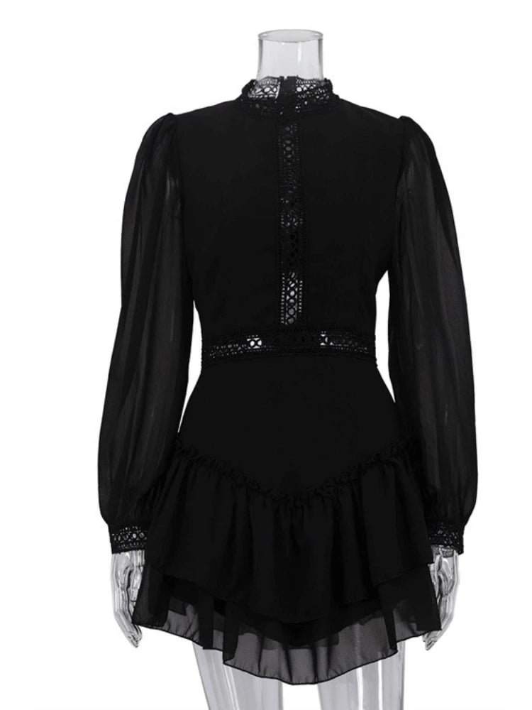 Black dress with sheer sleeves and ruffled skirt on a mannequin against a white background