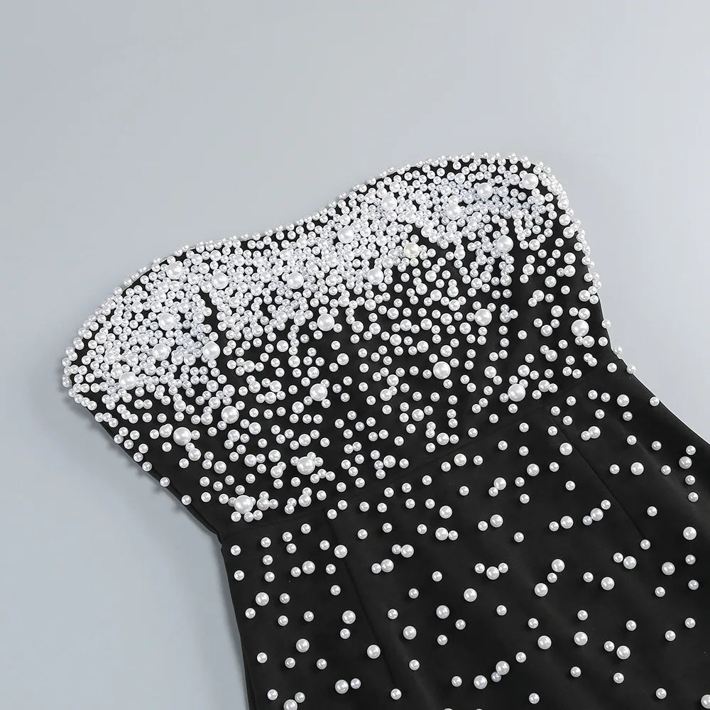 Black dress with white pearl embellishments on a gray background