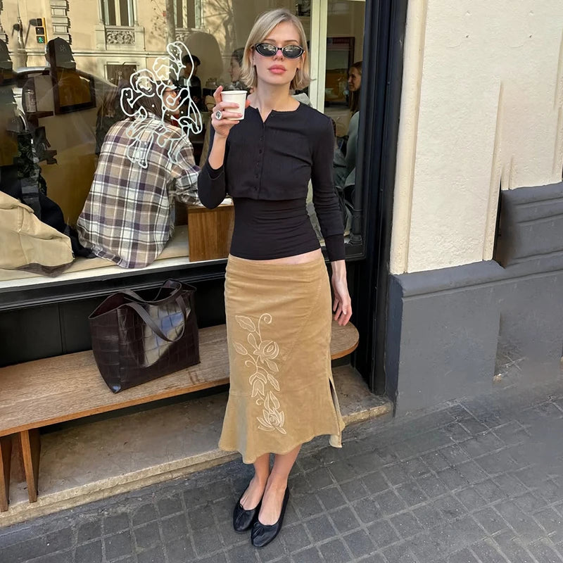 Woman in black top and beige skirt standing outside a store