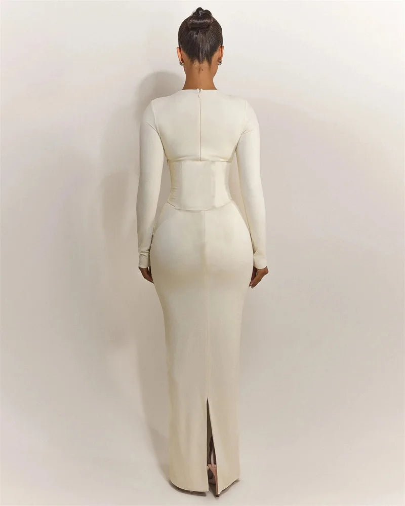 Person wearing a white long-sleeve dress with a slit on a plain background