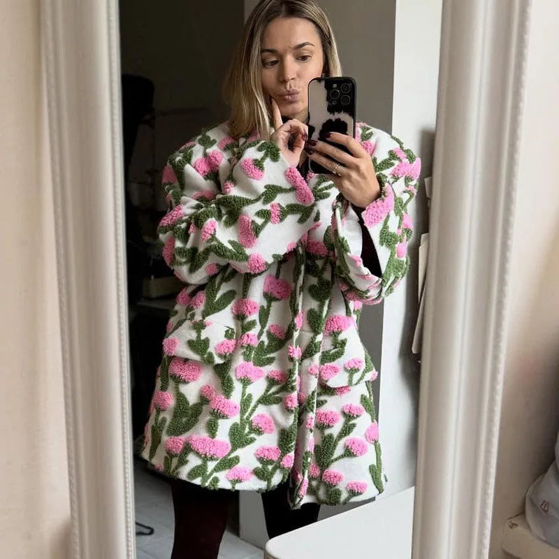 Woman wearing a floral patterned coat taking a mirror selfie.