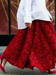 Person wearing a white shirt and red floral pants with pink shoes, standing against a blurred background.