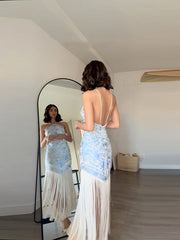 Woman trying on a blue and white dress in front of a full-length mirror.