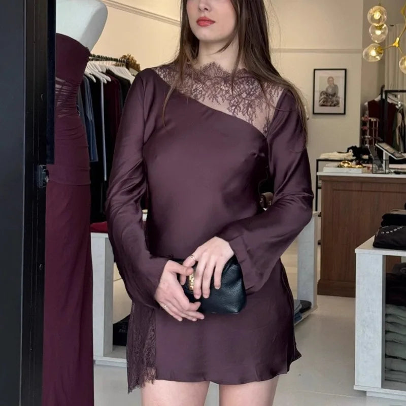 Woman wearing a dark purple dress with lace details in an indoor setting.