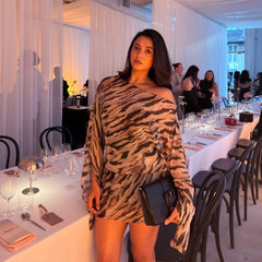 A woman poses in a one-shoulder zebra print mini dress