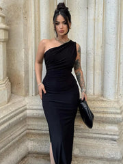 Woman in a black one-shoulder dress standing on stone steps with classical architecture.