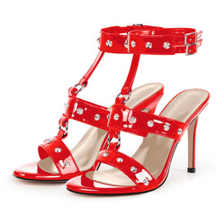 Red patent leather stiletto sandals with studded ankle strap and T-strap detail.