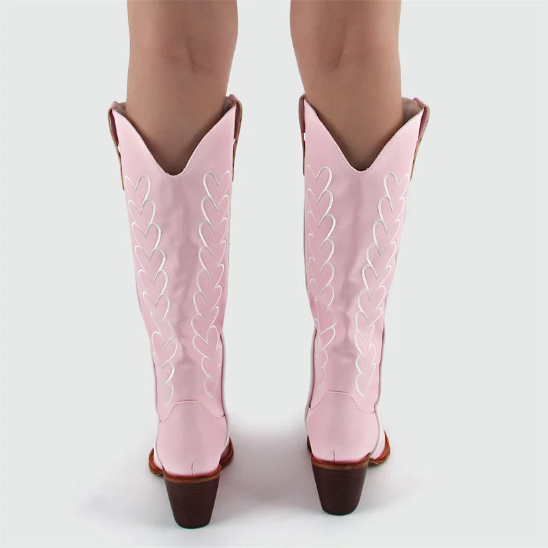 Pink cowboy boots with white stitching on a white background