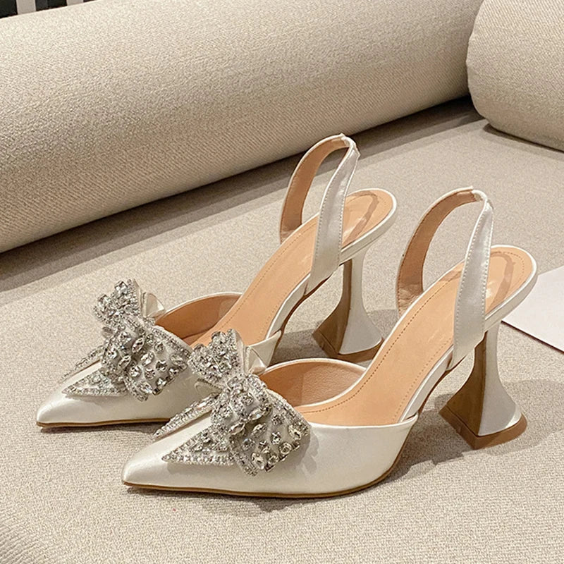 White high-heeled shoes with decorative bows on a light background