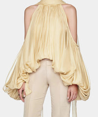 Woman wearing a beige halter top with flowing sleeves on a white background, brand 'Modphy' visible.