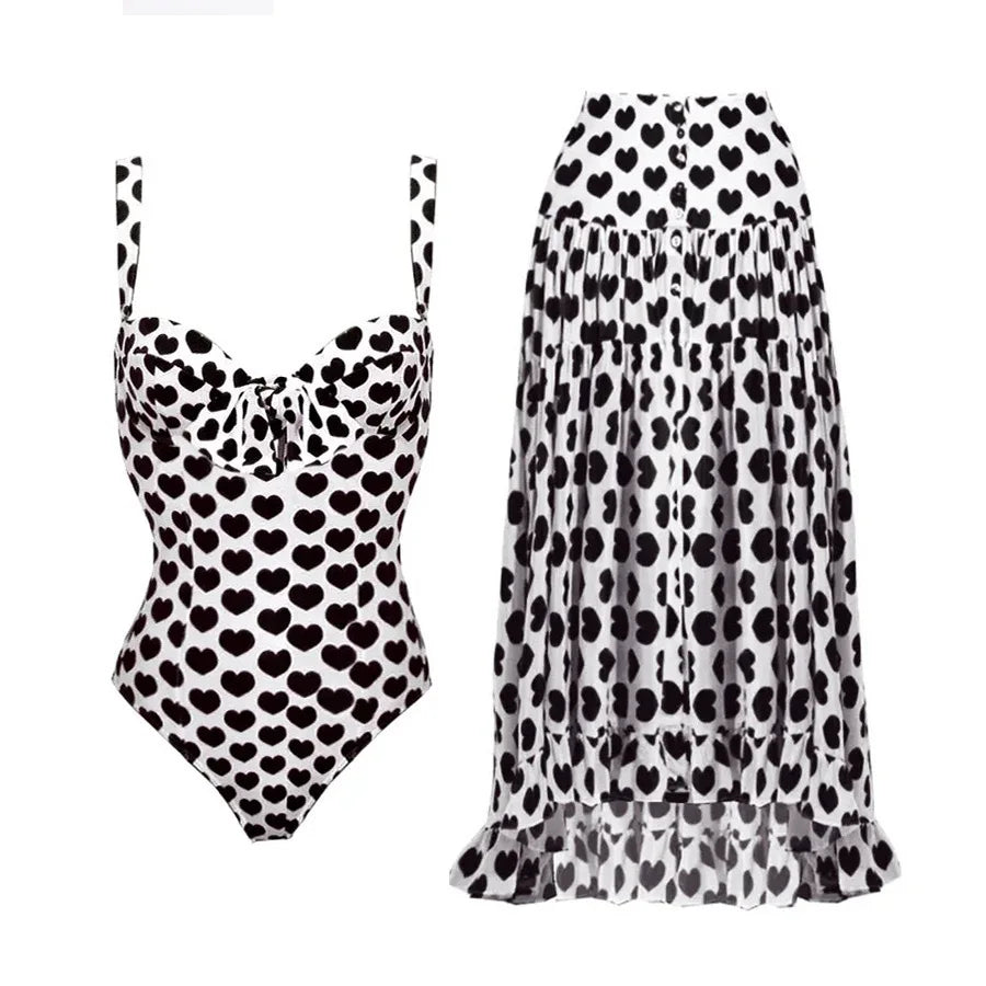 Black heart print one-piece swimsuit with a matching high-low ruffled skirt.