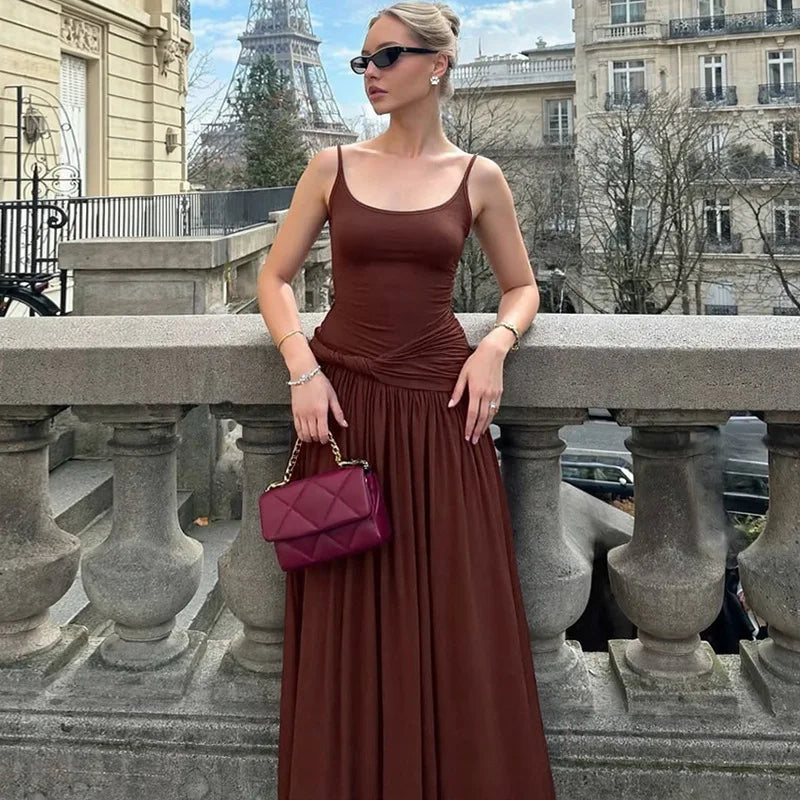 Woman in a brown dress with a red handbag standing in front of the Eiffel Tower.