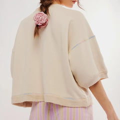 Person wearing a beige jacket with a pink flower in their hair against a white background