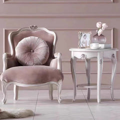 Pink armchair with decorative pillow and side table in a room with pink walls.