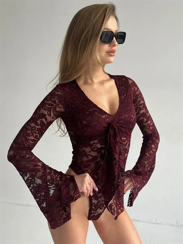Woman wearing a burgundy lace dress with long sleeves on a plain background