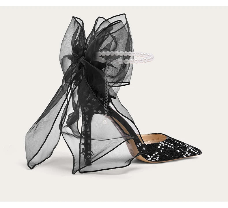 Black high-heeled shoes with sheer black ribbons on a white background
