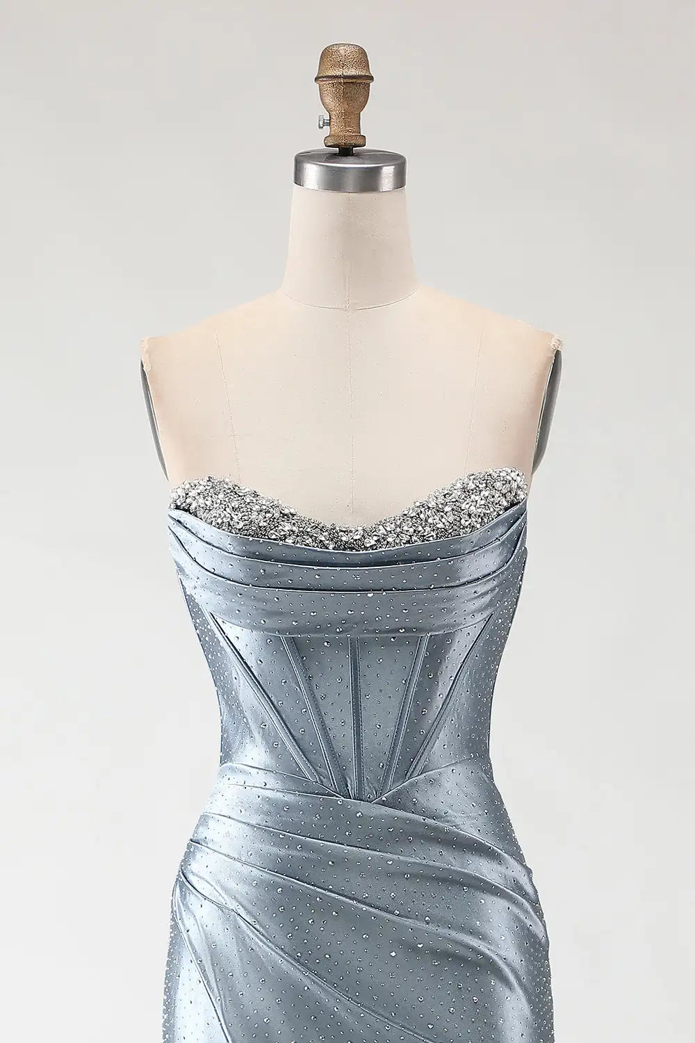 Silver evening gown on a mannequin with a plain background