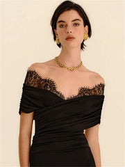 Woman wearing a black off-shoulder dress with lace detailing on a beige background