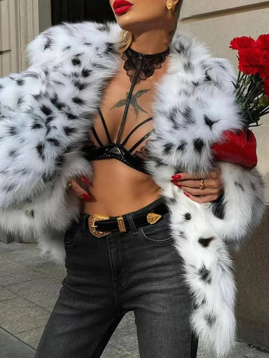 Person wearing a black and white fur coat holding red roses, standing outdoors.