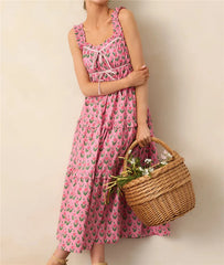Woman in a pink floral dress holding a woven basket against a plain background