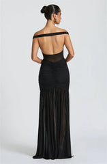 Black off-shoulder evening gown with sheer panels on a white background
