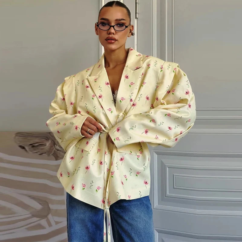 Person wearing a light yellow floral blouse with blue jeans in an indoor setting.