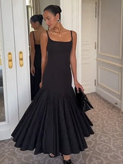 Woman in a black evening gown standing in a room with decorative walls.