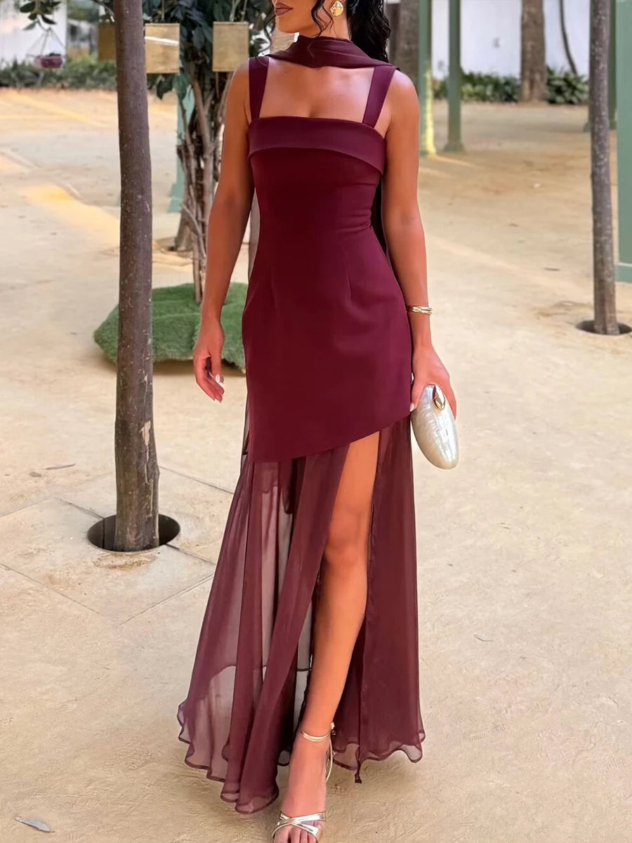 Woman wearing a burgundy dress with a high slit on a sidewalk.