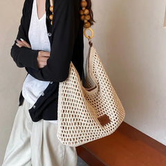 Person holding a woven handbag with a neutral background