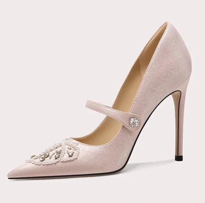 Pink high-heeled shoe with decorative strap on a light gray background