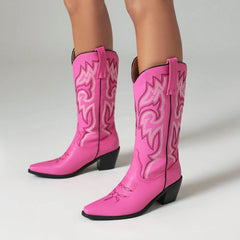 Pink cowboy boots with intricate designs on a light gray background