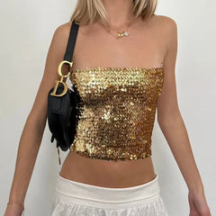 Person wearing a gold sequin top and white pants with a black handbag.