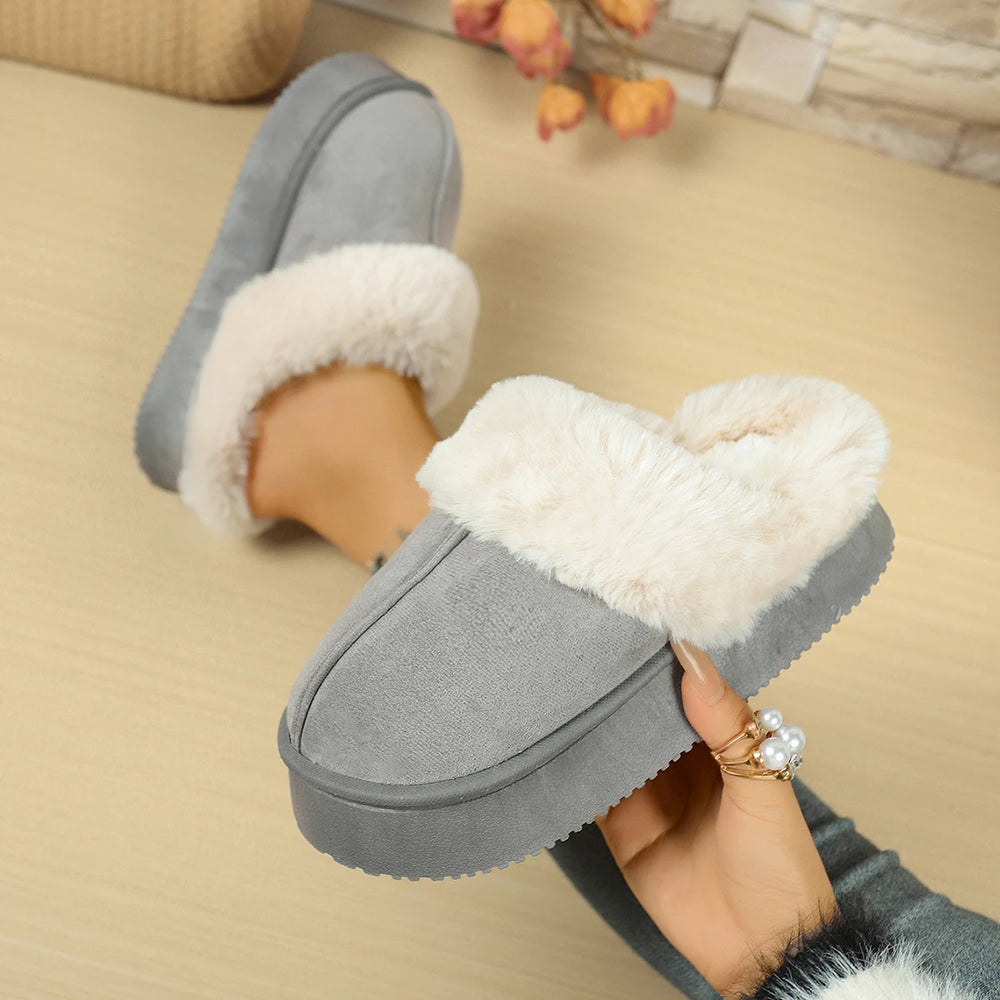 Gray slippers with white fur lining worn by a person on a beige surface.