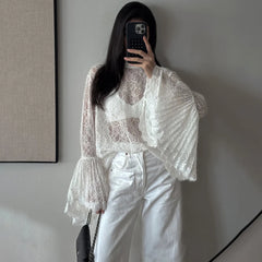 Person wearing a white lace top and white pants taking a mirror selfie.