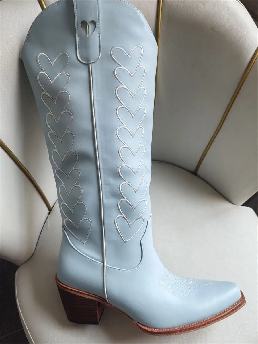Light blue cowboy boot with heart patterns on a white chair.